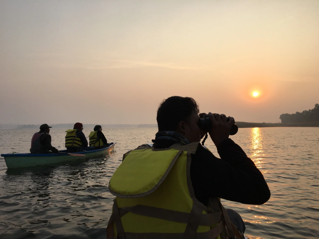 Guests birdwatching from boats at sunset