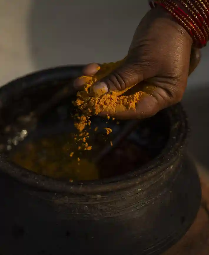Spices being added to a traditional cooking pot