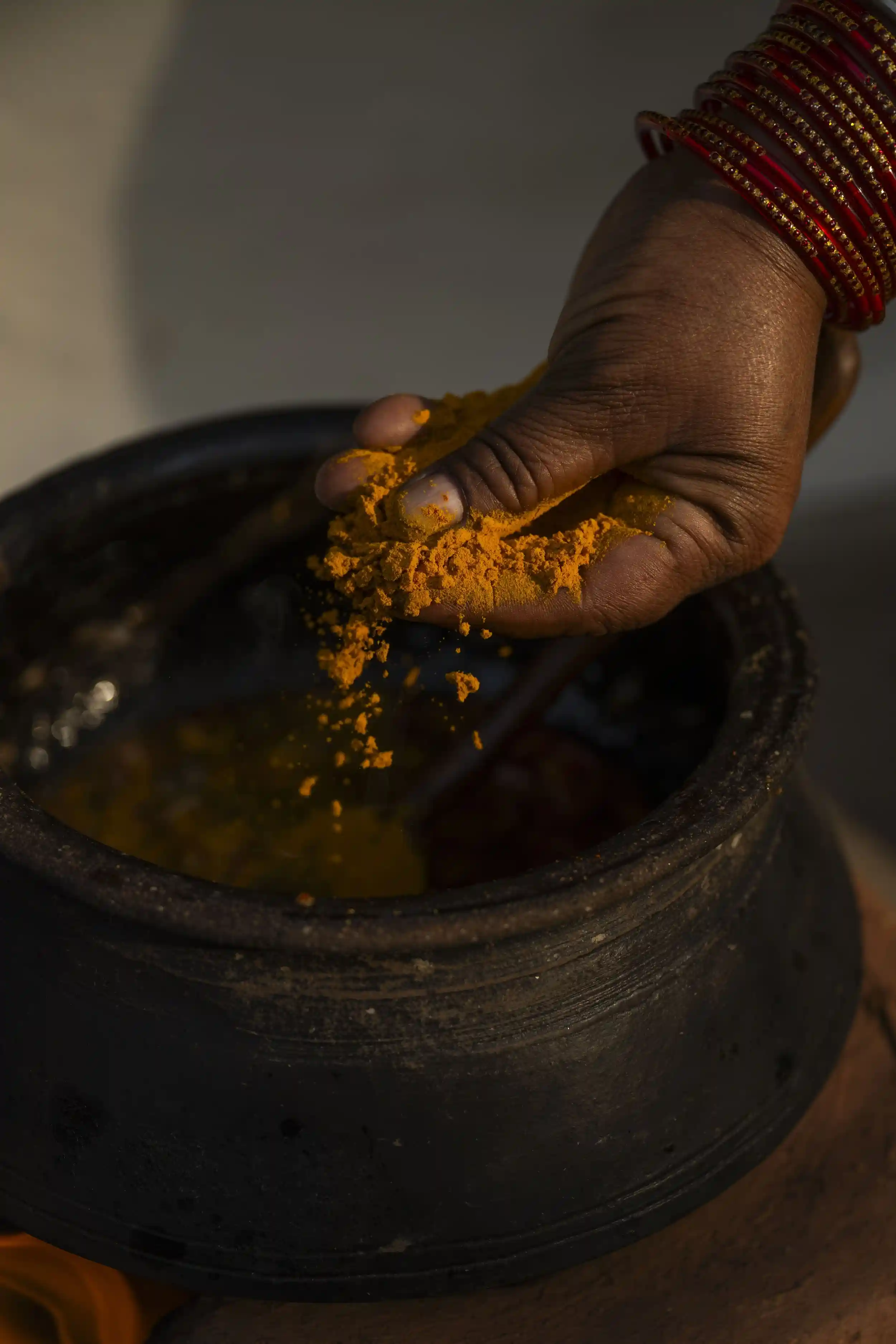 Spices being added to a traditional cooking pot