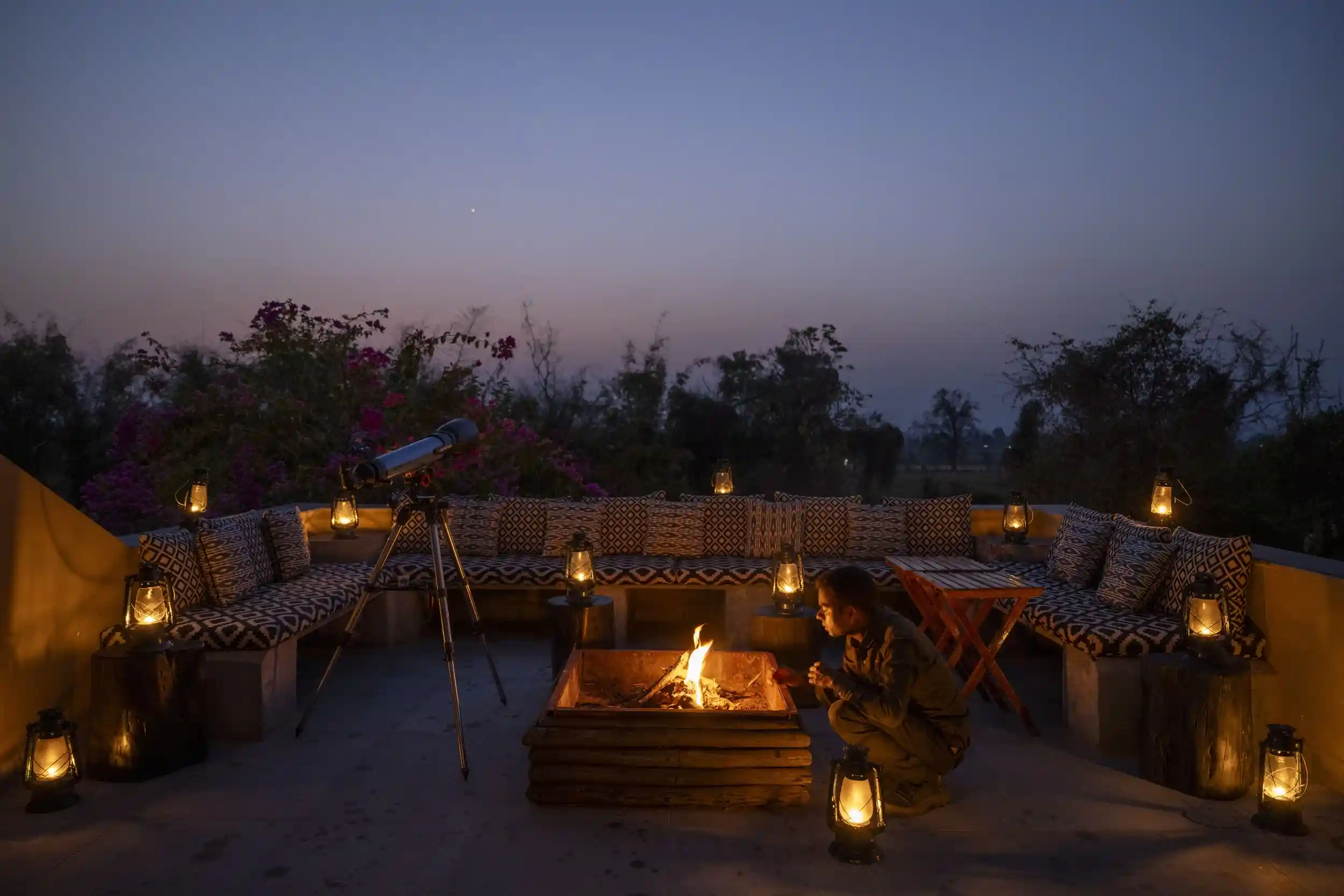 Open-air terrace arranged around a fire at dusk